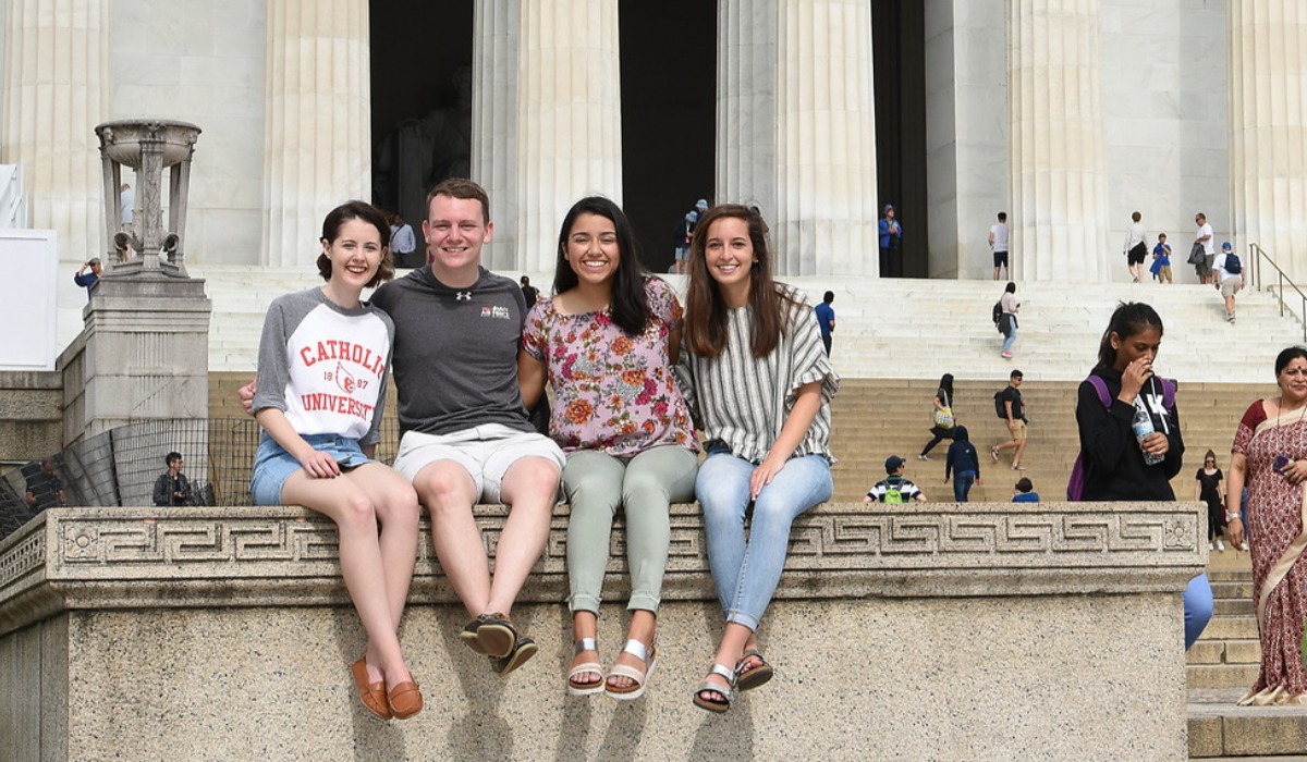 Four students sitting on the Lincoln Memorial